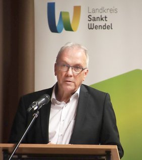 Landrat Udo Recktenwald steht an einem Rednerpult, vor ihm ein Mikrofon.