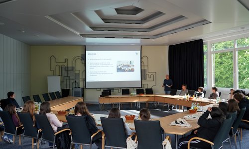 Schüler:innen sitzen im Sitzungssaal des Landratsamtes, der Landrat hält einen Vortrag.